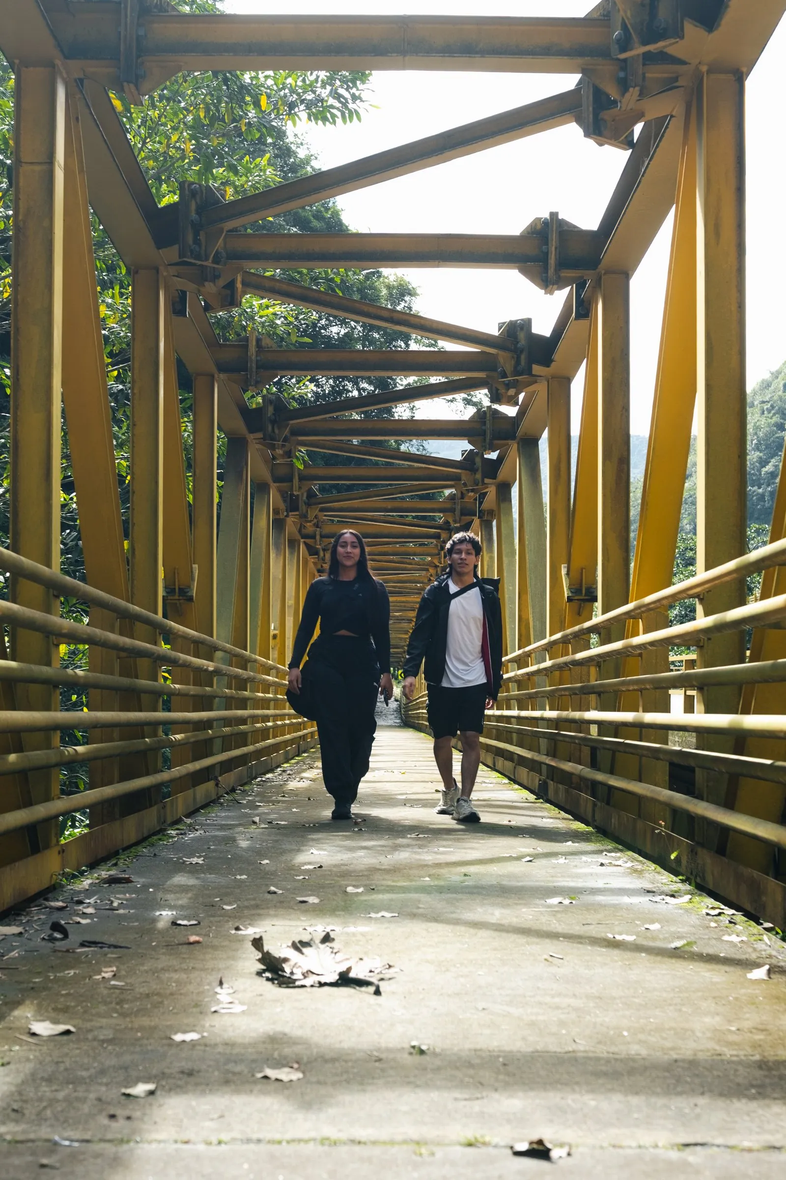 Dos personas cruzando un puente amarillo a contraluz